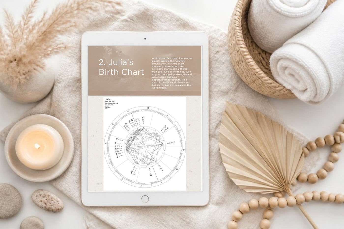 A personalized birth chart guide on an iPad in a calm spa setting with a candle, towels and dried flowers